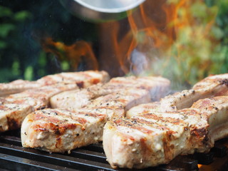 a man pours alcohol on the meat on the grill. roasting steaks on the fire. flambé.flamber.