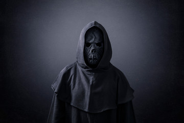 Scary figure in hooded cloak in the dark - obrazy, fototapety, plakaty