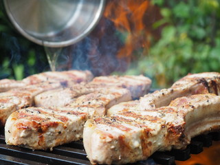 a man pours alcohol on the meat on the grill. roasting steaks on the fire. flambé.flamber.