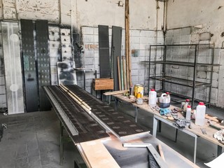 Old workshop carpentry woodwork for working with wood, plywood and painting. On the table there are jars of solvent and varnish, an industrial manufacturing room with boards. Handmade - DIY with metal