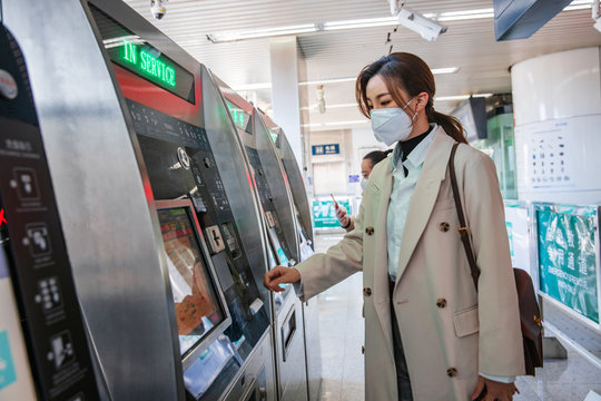 Young woman wearing a mask in the subway station to use automatic machines