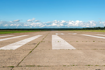 The runway of a rural small airfield against a blue sky with clouds of the airfield. Lonely...