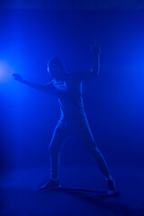 Fototapeta premium A man in with an unusual haircut mohawk in blue smoke waving his hands up