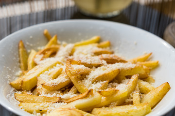 French fries with cheese on top in a white plate! Selective focus 