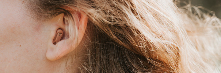 Naklejka premium small intra channel hearing aid in the ear of a woman. banner