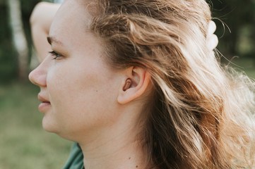 small intra channel hearing aid in the ear of a woman