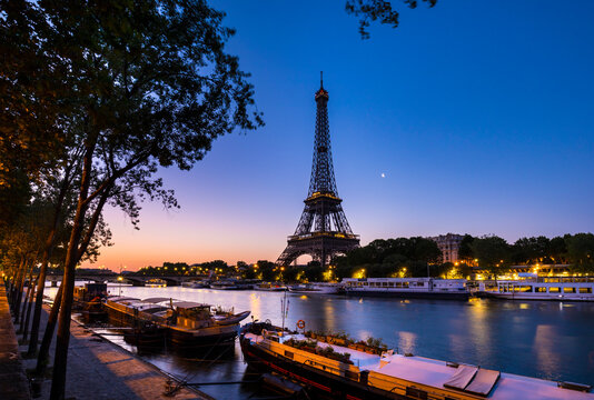 Eiffel Tower by Seine river against clear blue sky at sunset, Paris, France