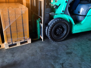 Worker driving forklift loading and unloading shipment carton boxes and goods on wooden pallet from container truck to warehouse cargo storage in logistics and transportation industrial 