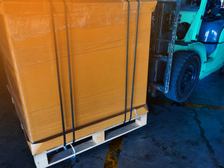 Worker driving forklift loading and unloading shipment carton boxes and goods on wooden pallet from container truck to warehouse cargo storage in logistics and transportation industrial 