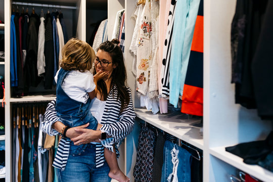 Happy mother carrying daughter while standing by closets in dressing room at home