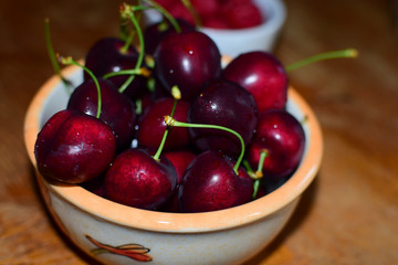 Sweet cherries in a ceramic bowl on a wooden table. Close-up