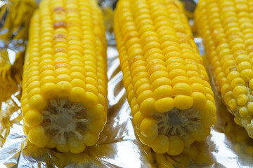 Young yellow fried sweet corn on craft paper. Delicious summer food. Close-up.