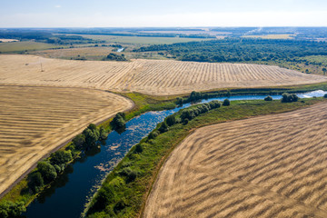 aerial photography of a bend in a river flowing through mown fields