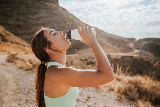 Athlete woman drinking water from a bottle in the mountains