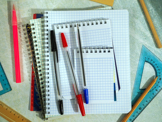 Notepads, notepads, pens, pencils, rulers and other office supplies on a green table surface....