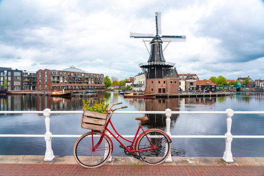 Netherlands, North Holland, Haarlem, Bicycle parked along railing of canal bridge with De Adriaan windmill in background
