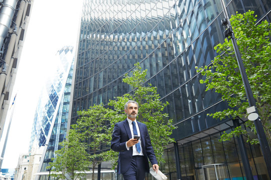 Businessman Texting Through Mobile Phone Outside Office Building In City