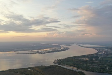 Fototapeta premium View from the drone to the river, bridge, factories in the evening. Cumulus clouds.