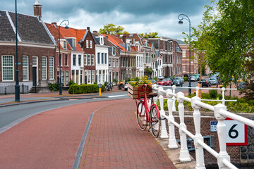 Netherlands, North Holland, Haarlem, Bicycle parked along railing of canal bridge with houses along Hooimarkt street in background