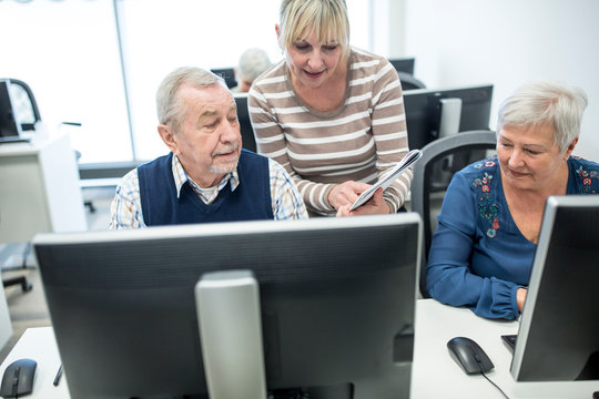 Active Seniors Attending Computer Course, Intructor Giving Advice