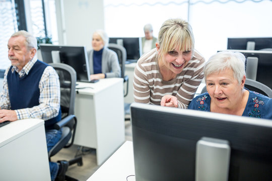Active seniors attending computer course, intructor giving advice