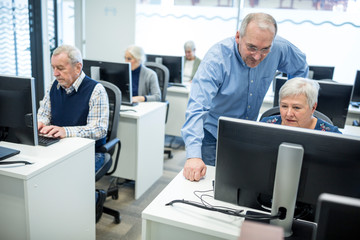 Active seniors attending computer course, intructor giving advice