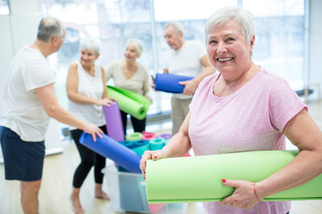 Happy senior woman holding yoga mat after class