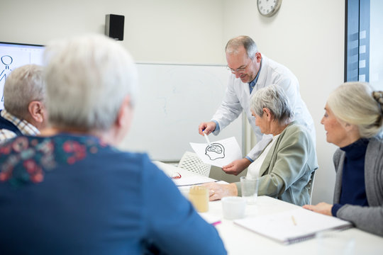 Doctor explaining brain functions to group of senior citizens