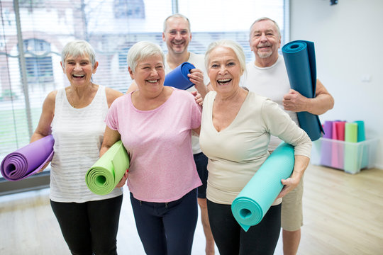 Group Of Happy Seniors Holding Mats For Yoga Class