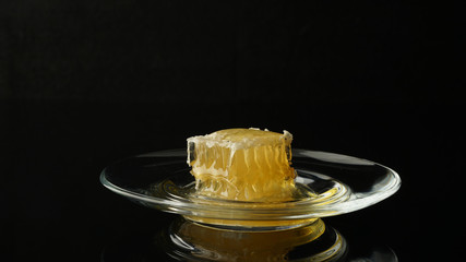 honey in combs on a transparent plate on a dark background