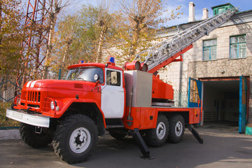 A large soviet red fire truck is preparing to leave.