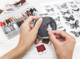 Woman embroider a butterfly. Process of making handmade embroidery. Hobby. Sewing tools. Remote...