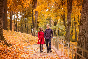 young couple walks in the autumn Park. Orange and yellow leaves around