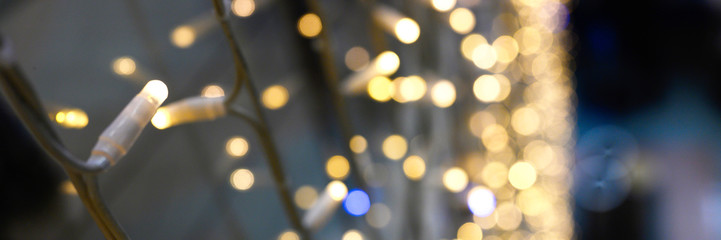 Obraz premium blurred glowing lights of garlands of golden color, bokeh. banner