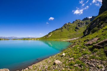 Fototapeta na wymiar Alpine mountain lake at the daytime, sunlight and colorful landscape