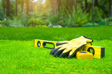 Artificial grass background with the tools against the beautiful garden