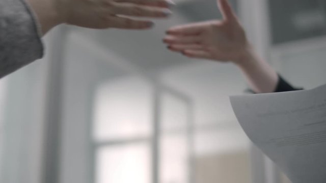 lady papers to businesswoman and shakes hands with her