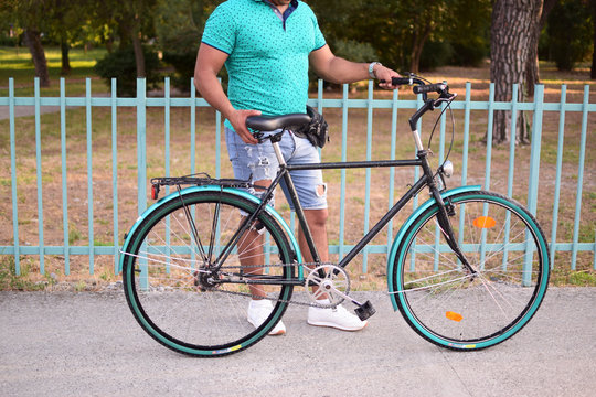 young man holding a bike, green bike, city bike