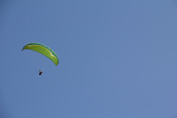 paragliding high in the blue sky on a summer sunny day. plenty of space for text