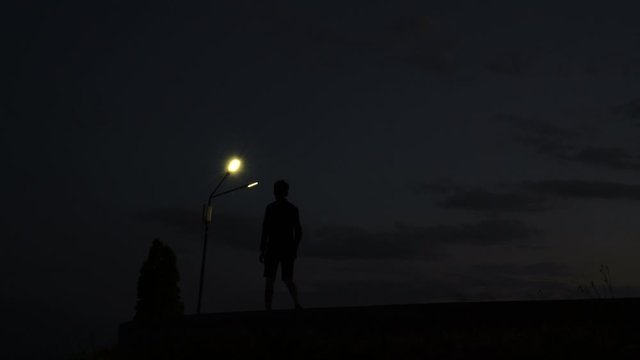 Silhouette of a walking young man, guy at sunset, sunrise, sundown, dusk, twilight, nightfall - 4K 