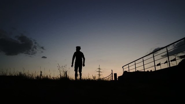 Silhouette of a walking young man, guy at sunset, sunrise, sundown, dusk, twilight, nightfall - 4K 