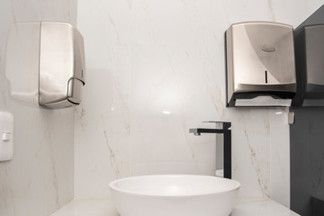 Lavabo con mezcladora sobre una base de mármol con dos dispensadores uno de jabón y otro de toallas sanitarias