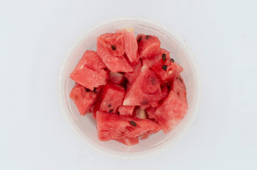 TOP VIEW OF FRESH WATERMELON IN PIECES INSIDE A PLASTIC LUNCH BOX on a white background,