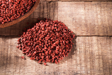 Annatto seeds in bowl on wooden background - Bixa Orellana.
