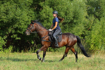 Beautiful equestrian girl riding horseback. Harmony of humans and animals