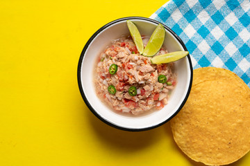 Canned tuna ceviche with chili pepper and tomato on yellow background