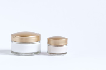 A set for skin care around the eyes and skin consisting of glass jars with cream and serum.