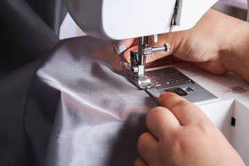 A man hem a curtain on a sewing machine. Sewing, hobbies, hobby, home improvement.