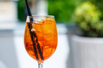 Refreshing light delicious summer aperol cocktail with ice and orange in a glass goblet, soft drink with straws for girls