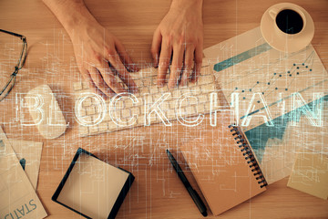 Double exposure of man's hands typing over computer keyboard and crypto currency theme hologram...